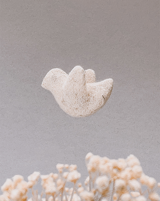 Ручно рађена птичица од вуне, као део Дедино вртешке, виси у ваздуху