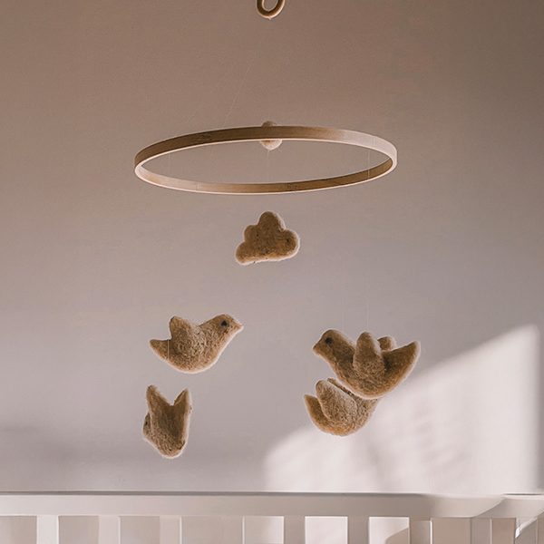 Ручно рађени украси од вуне у облику птичица изнад бебиног кревеца